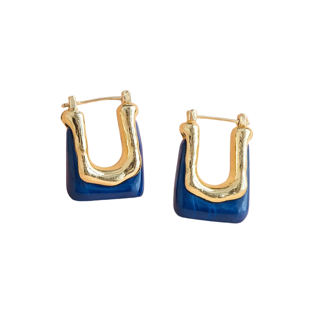 A pair of gold and blue geometric hoop earrings on a soft pink background.