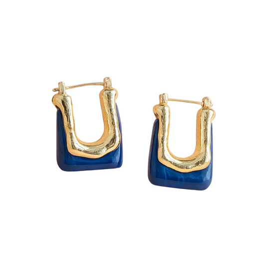 A pair of gold and blue geometric hoop earrings on a soft pink background.