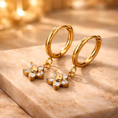 Gold hoop earrings with star-shaped pendants on a marble surface