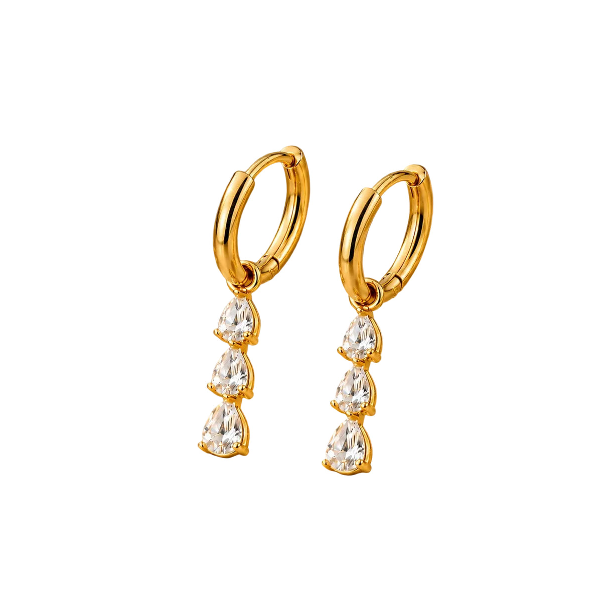 A pair of gold huggie hoop earrings with dangling teardrop-shaped clear gemstones, displayed on a draped gold satin fabric.